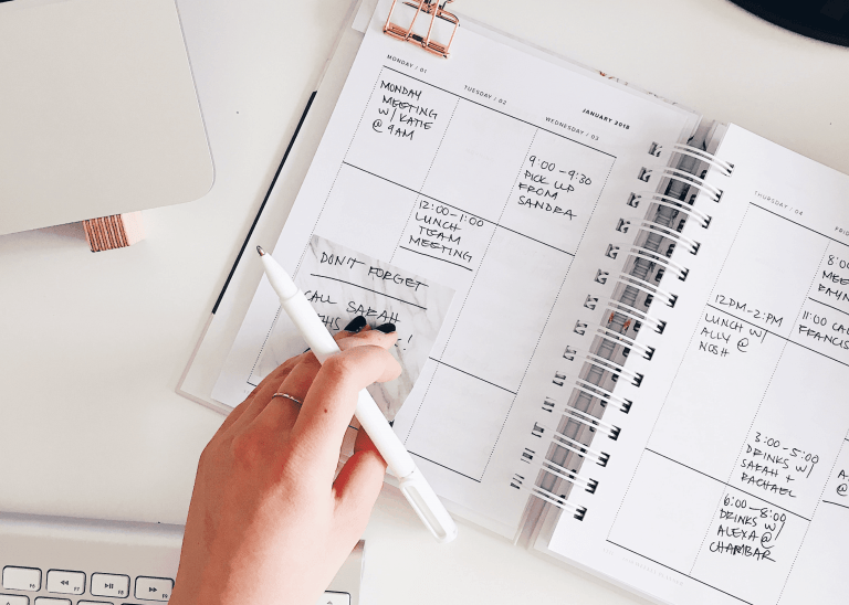 Woman writing on her paper planner to show time blocking for productivity