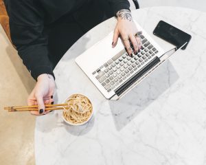 Person working on computer while eating to demonstrate multitasking